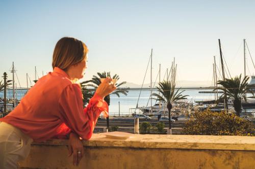 a woman sitting on a wall looking at a marina at Birkin Porto 1870 in Cagliari