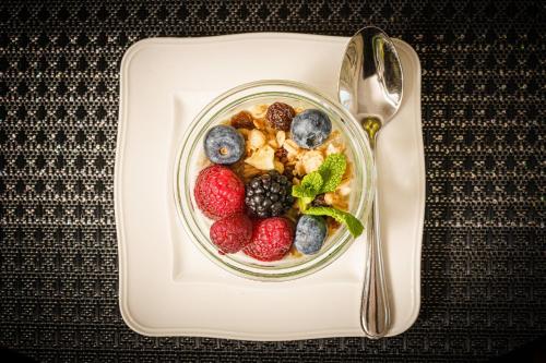 a bowl of fruit and berries on a plate with a spoon at Birkin Porto 1870 in Cagliari