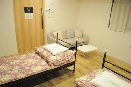a room with a bed, table, chair and a lamp at 04village Namba in Osaka