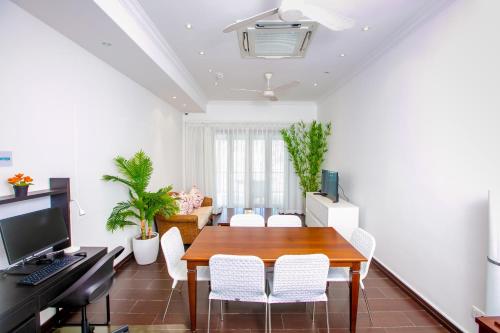 a dining room with a wooden table and white chairs at Eden Studios in Mahe