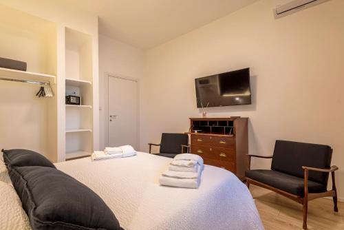 a bedroom with a bed and a couch and a tv at RelaisApartments PORTO in Alghero
