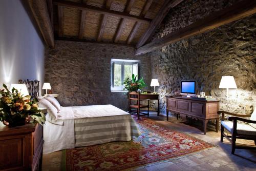 Schlafzimmer mit einem Bett, einem Schreibtisch und einem TV in der Unterkunft Casa la Carrubbazza in San Gregorio di Catania