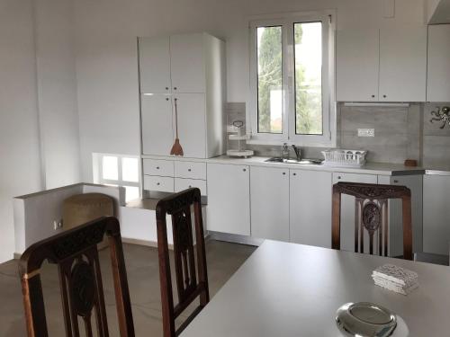 a kitchen with white cabinets and a table and chairs at Bay View Villas in Methoni