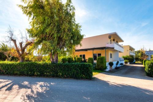 a yellow building with a tree and a driveway at Litsas Studios in Phanaes