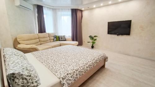 1 dormitorio con cama, sofá y TV en Шикарные апартаменты в центре en Perm