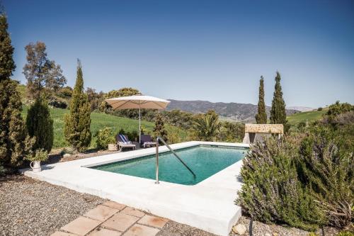 uma piscina num jardim com um guarda-sol em Rosas Cantares: Casa Siri em Pizarra