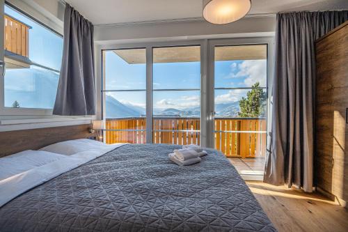 a bedroom with a bed and a large window at AlpenParks Hotel & Apartment Alpendorf in Sankt Johann im Pongau