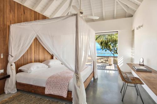 a bedroom with a canopy bed and a desk at Villa Trois Couleurs Bleu in Saint-Gilles les Bains