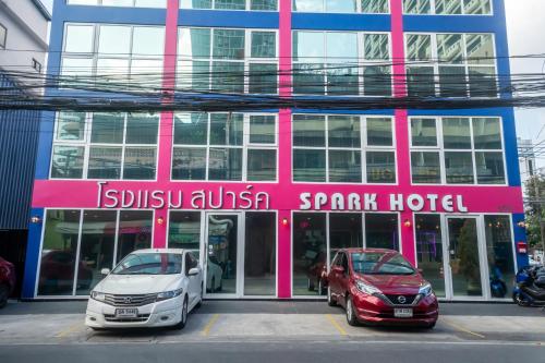 two cars parked in front of a pink and blue building at Spark Hotel - MRT Queen Sirikit - SHA Extra Plus Certified in Bangkok
