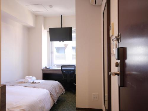 a room with a bed and a desk and a window at Hotel Comfybed Ginza in Tokyo