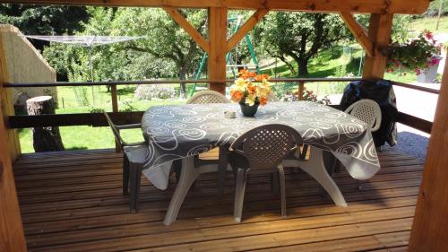 un tavolo con sedie e un vaso di fiori su una terrazza di L'ATELIER, chalet 3* a Vecoux