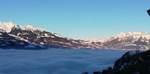 a view of a mountain covered in snow and clouds at Hotel Restaurant Kulm in Triesenberg