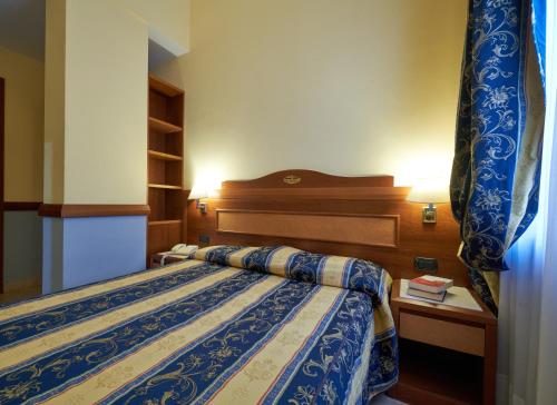 a bedroom with a bed with a blue and white comforter at Hotel Ristorante La Piana in Telese