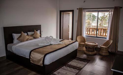 ein Schlafzimmer mit einem großen Bett und einem Balkon in der Unterkunft Shivaji Inn Kaziranga in Kāziranga
