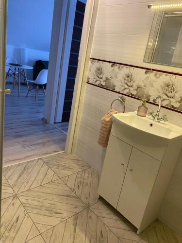 La salle de bains est pourvue d'un lavabo et de carrelage. dans l'établissement Apartamenty - Pod Wierzbami, à Dwikozy