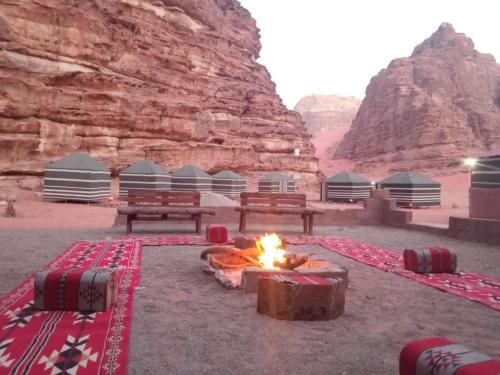 un campo con panchine e un fuoco nel deserto di Wadi Rum White Mountain Camp a Wadi Rum