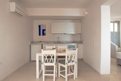 a kitchen with white cabinets and a table and chairs at Ikia Kriton in Imerovigli