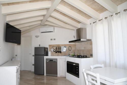a kitchen with white walls and a ceiling with beams at La casa di Ziu Menicu in Cannigione