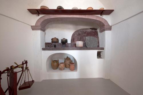 a hallway with a shelf with pots and vases on it at Ikia Kriton in Imerovigli