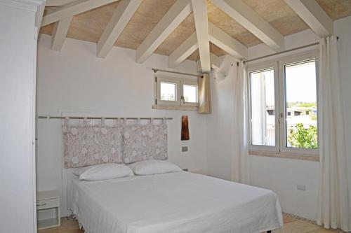 a bedroom with a white bed and a window at La casa di Ziu Menicu in Cannigione