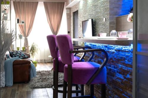 a room with purple chairs and a brick wall at Spa Apartman URBAN Life ZAJEČAR in Zaječar