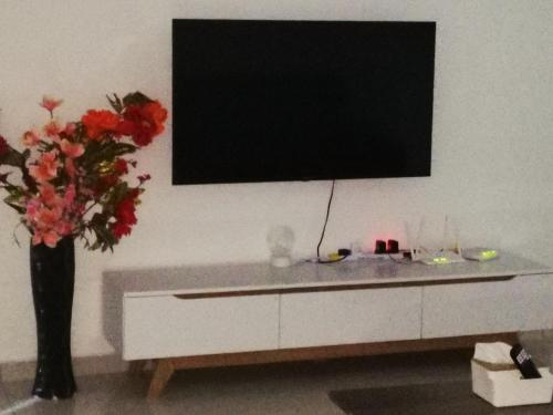 a living room with a tv and a vase with flowers at 48 悠之处NO . 48, PERSIARAN ALAM IMPIAN 3 VILLA RIADAH ALAM IMPIAN PANGKOR, 32300 PANGKOR , PERAK. in Pangkor