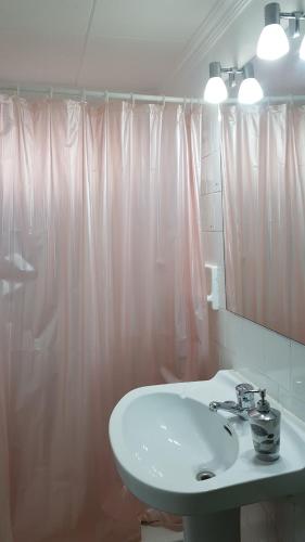 a bathroom with a sink and a pink shower curtain at Can Marti in Alfara de Carles