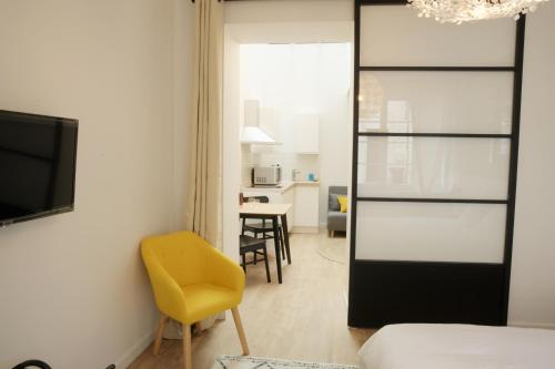une chambre avec une chaise jaune et une chambre avec une table dans l'établissement T2 avec verrière situé en hyper centre avec wifi, linge, draps, savons et serviettes fournis, à Cognac