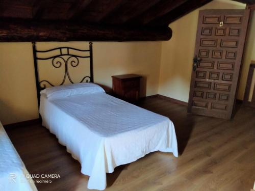 a bedroom with a white bed and a door at Casa Rural la Cancha I in Navalacruz