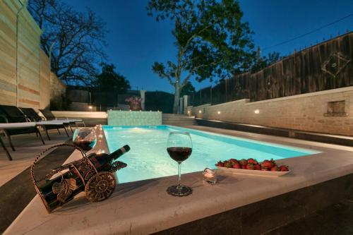 a glass of wine and a bowl of fruit in a swimming pool at Villa Patrick-Luxury stone house in the center of Istria in Pazin