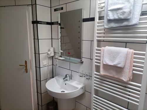 a bathroom with a sink and a mirror and towels at Hotel An der Karlstadt in Bremerhaven