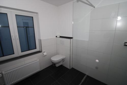 a white bathroom with a toilet and a window at Ferienwohnung Oststraße 37 in Schmallenberg