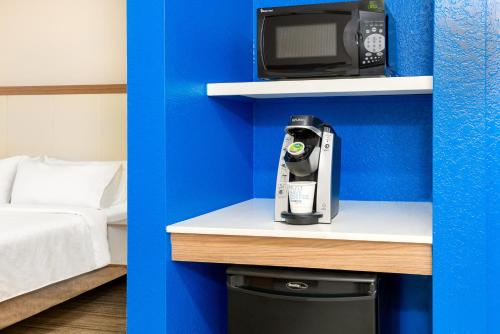 a coffee maker and a microwave on a shelf in a room at Holiday Inn Express Hotel & Suites Bonita Springs/Naples by IHG in Bonita Springs
