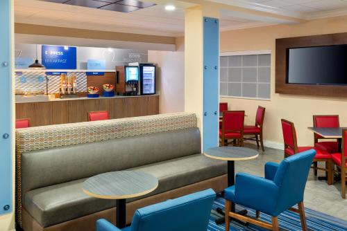 a waiting room with tables and chairs and a tv at Holiday Inn Express Hotel & Suites Bonita Springs/Naples by IHG in Bonita Springs