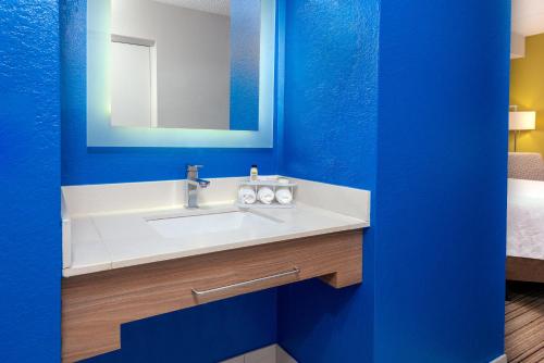 a bathroom with a white sink and a blue wall at Holiday Inn Express Hotel & Suites Bonita Springs/Naples by IHG in Bonita Springs