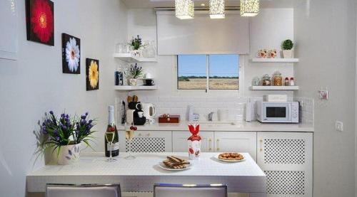 a white kitchen with a table and a microwave at סוויטות דה בלנקה in Had Nes