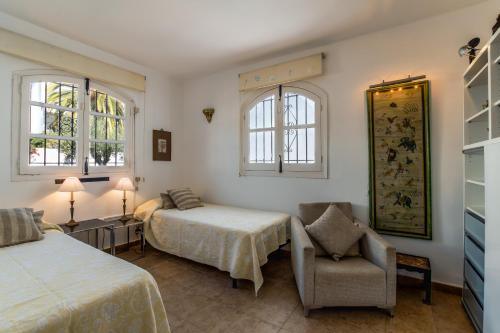 - une chambre avec deux lits, une chaise et deux fenêtres dans l'établissement Las Lilas, Nerja, à Nerja