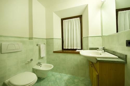 a white bathroom with a toilet and a sink at Residence Deborah in Madesimo