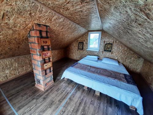 an attic bedroom with a bed and a brick fireplace at Загородный дом на берегу реки Самара in Dnipro