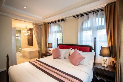 a bedroom with a large bed and a bathroom at Nanta Glam CM Hotel & Residences in Chiang Mai