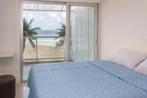 1 dormitorio con cama y vistas a la playa en Asturias Mall & Suítes, en Guarujá