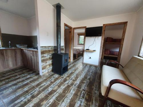 Una sala de estar con una estufa de leña y un sofá. en Cabañas Olas del Bosque, en Pichilemu