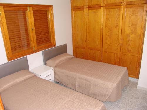 a bedroom with two beds and wooden cabinets at ACOGEDOR Apto. 6 pax, TABLERO 1, cerca PLAYA DEL INGLES in El Tablero