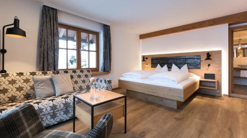 une chambre d'hôtel avec un lit et un canapé dans l'établissement Wohlfühlhotel Berwanger Hof, à Obermaiselstein