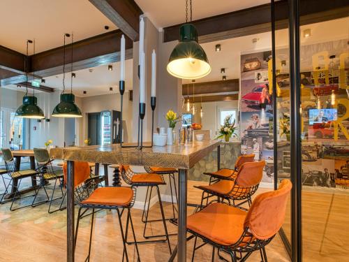 a bar in a restaurant with orange chairs at Vienna House Easy by Wyndham Ingolstadt in Ingolstadt