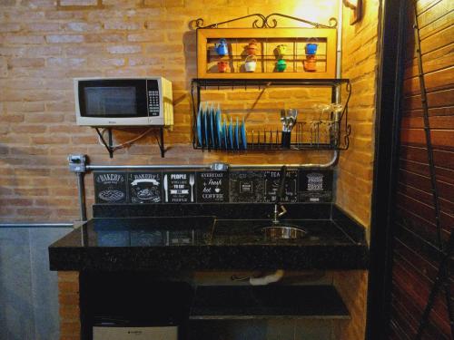 a kitchen with a counter with a microwave and a sink at La Villa Chalés in Serra Negra
