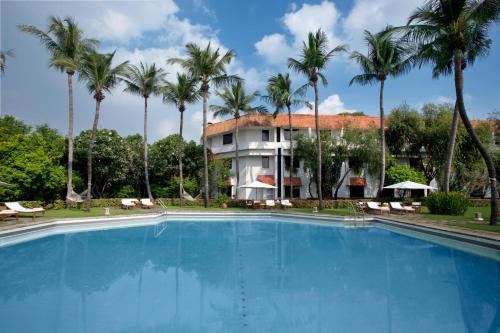 a large swimming pool in front of a building with palm trees at Trident Chennai in Chennai