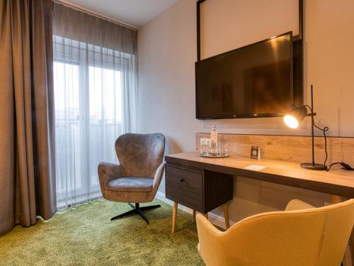 a room with a desk and a chair and a television at Vienna House Easy by Wyndham Ingolstadt in Ingolstadt