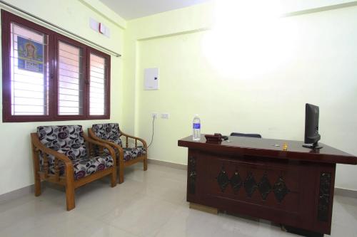 a room with a desk and a chair and a television at Lakshana Service Apartment - Big Temple Thanjavur in Thanjāvūr