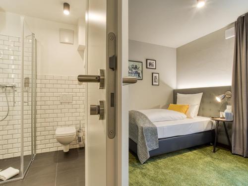 a bedroom with a bed and a bathroom with a shower at Vienna House Easy by Wyndham Ingolstadt in Ingolstadt